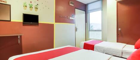 A hotel room with two beds, a television, a window, and a wall with a decorative design.