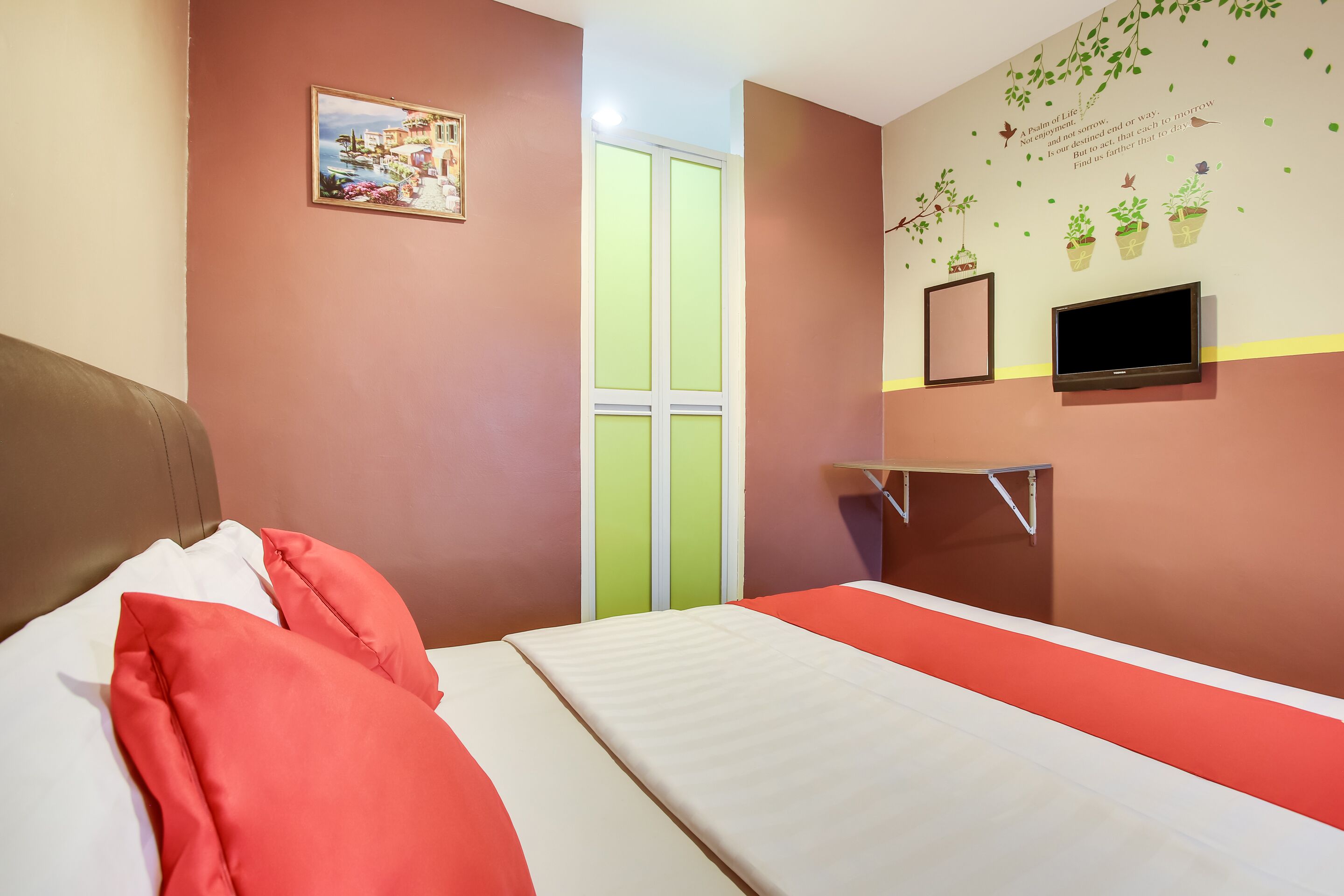 Ein Schlafzimmer mit Bett, Kissen, Fernseher und einer Wand mit einem Bild und Dekoration.