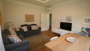 A modern living room with a sofa, a dining table, and a TV.