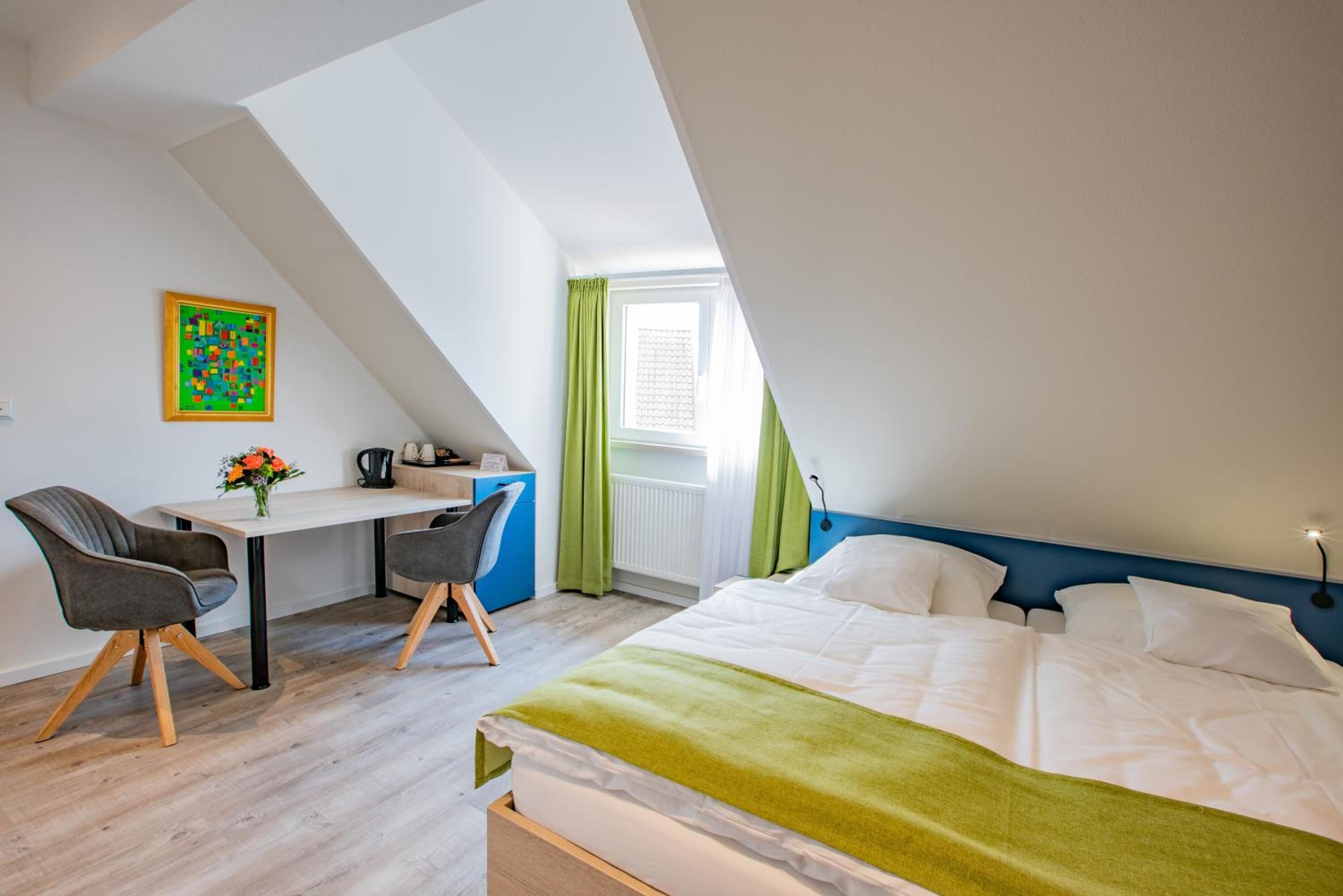 Een moderne slaapkamer met een bed, een bureau en twee stoelen.