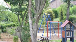 A playground with a swing set, climbing frame, and a small wooden structure. - Caesaro Hotel & Pizzeria (Hagen am Teuteburger Wald)