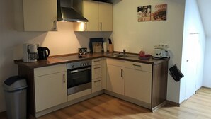 Een kleine keuken met een fornuis, spoelbak en koffiezetapparaat.