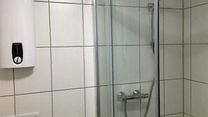 Een douche met glazen wanden, een handdouche en een bedieningspaneel aan de muur.