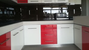 A kitchen with red and white cabinets, a black countertop, and a microwave. - Modern and cozy apartment (Pereybere)