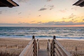 A wooden boardwalk leading to a beach with waves and a sunset in the background. - Dune It Wright at Carolina Shores 8BR Oceanfront + Pets Stay Free (Nags Head)