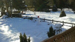 A snow-covered backyard with a wooden deck, a snowman, and a wooden fence. - Ferienwohnungen an der Loipe (Braunlage)