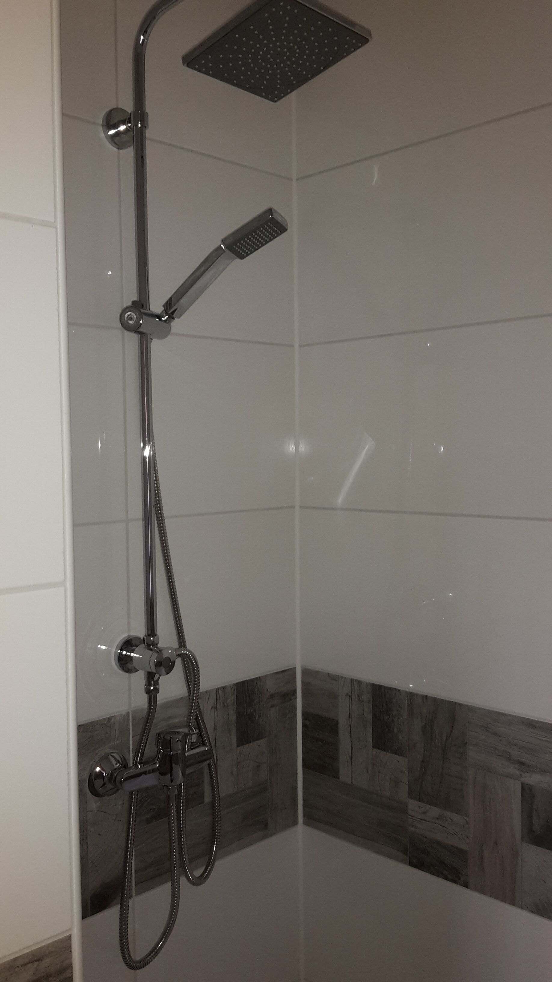 A shower with a handheld showerhead, a fixed showerhead, and a rain showerhead.