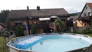An above-ground swimming pool with a ladder and inflatable floatation devices. - Ferienwohnungen an der Loipe (Braunlage)