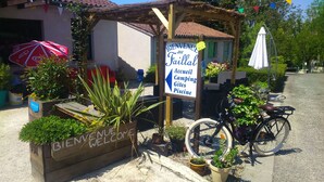 Un letrero de bienvenida para un camping con comodidades como piscina e instalaciones para acampar.