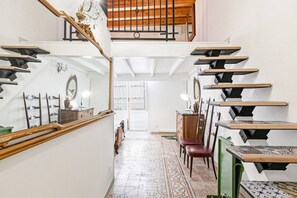 A staircase with a wooden handrail and black railings, leading to a second floor. - GuestHost - Norman Palace Stylish Apartment (Palermo)