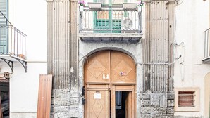 Ein Gebäude mit großem Bogenportal, einem Balkon mit Metallgeländer und einem kleinen Fenster auf der rechten Seite.