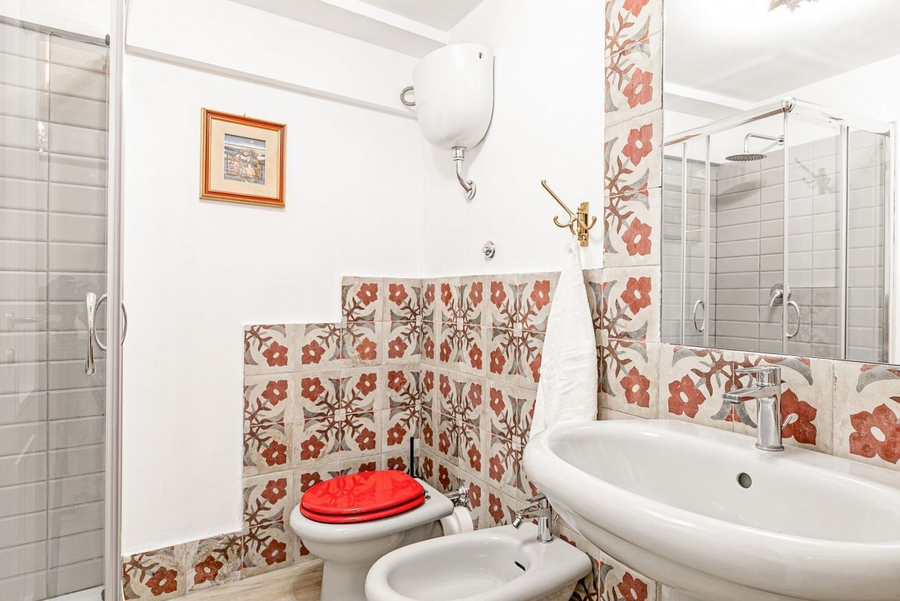 A bathroom with a shower, toilet, bidet, and sink.