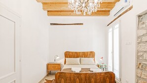 Ein Schlafzimmer mit einem hölzernen Bett, einer Chandelier, einem Nachttisch und einer Steinwand.