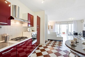 Une cuisine moderne avec des meubles de couleur rouge, une cuisinière à gaz et un carrelage à motifs.