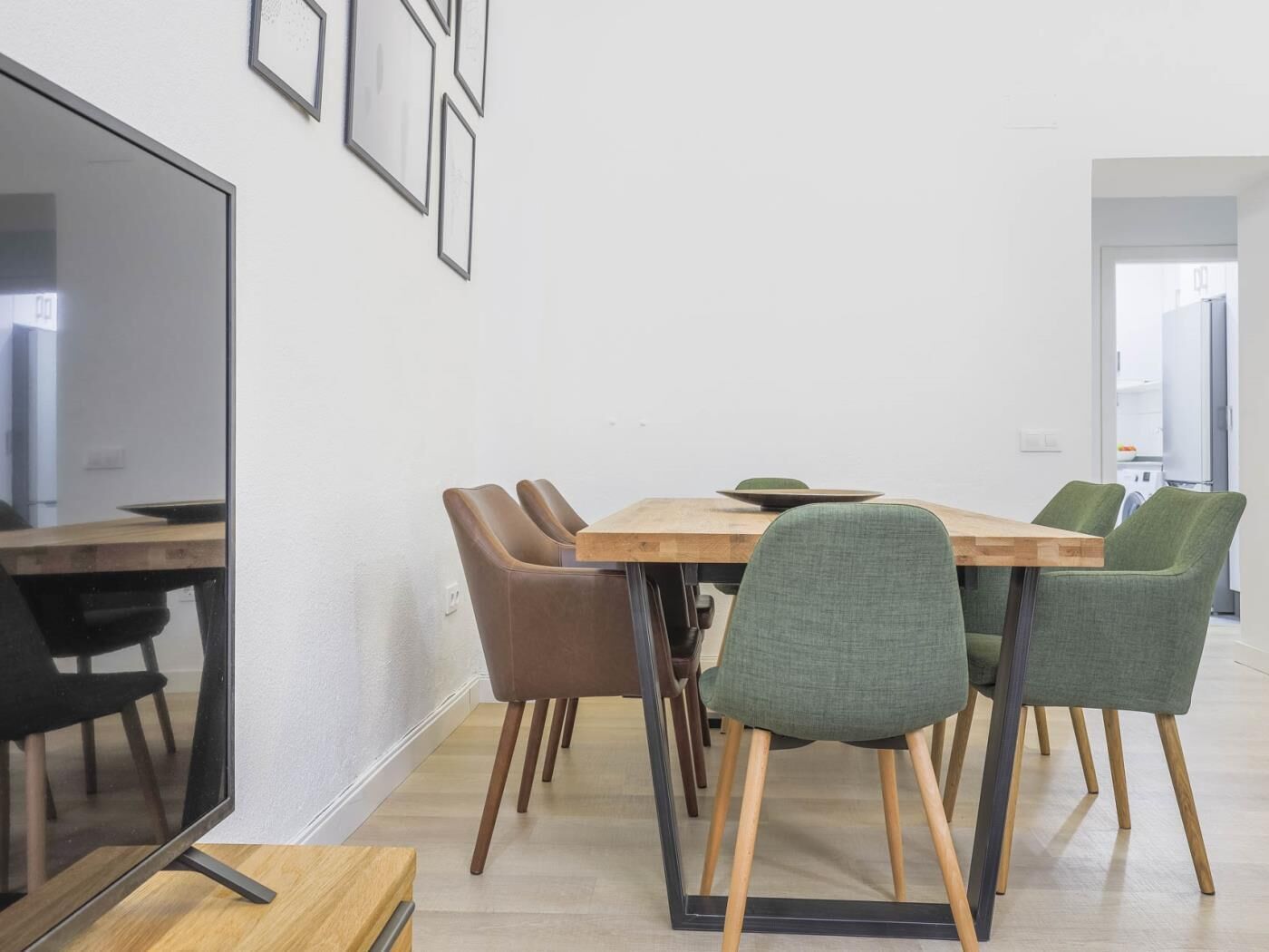 Un espace repas moderne avec une table en bois et quatre chaises, dont une est verte.