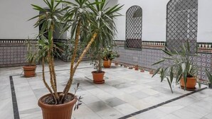 Een binnenplaats met plantenpotten, betegelde vloer en decoratieve wandtegels.