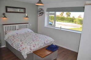 Une chambre à coucher avec un lit, une fenêtre, une table de chevet et un miroir.