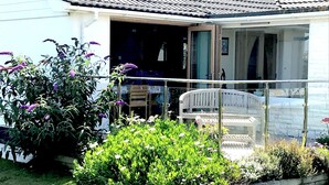 Een huis met balkon, een stoel en een tuin vol planten en bloemen.