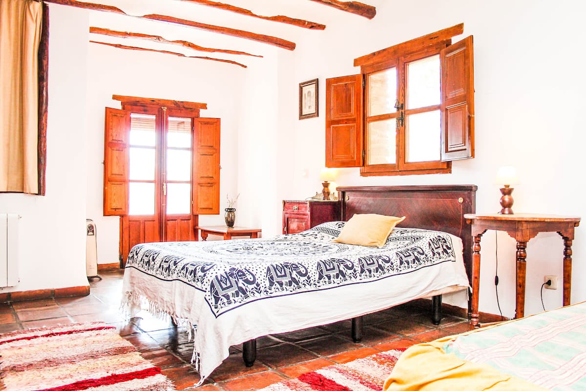 A bedroom with a bed, wooden furniture, and a window with shutters.