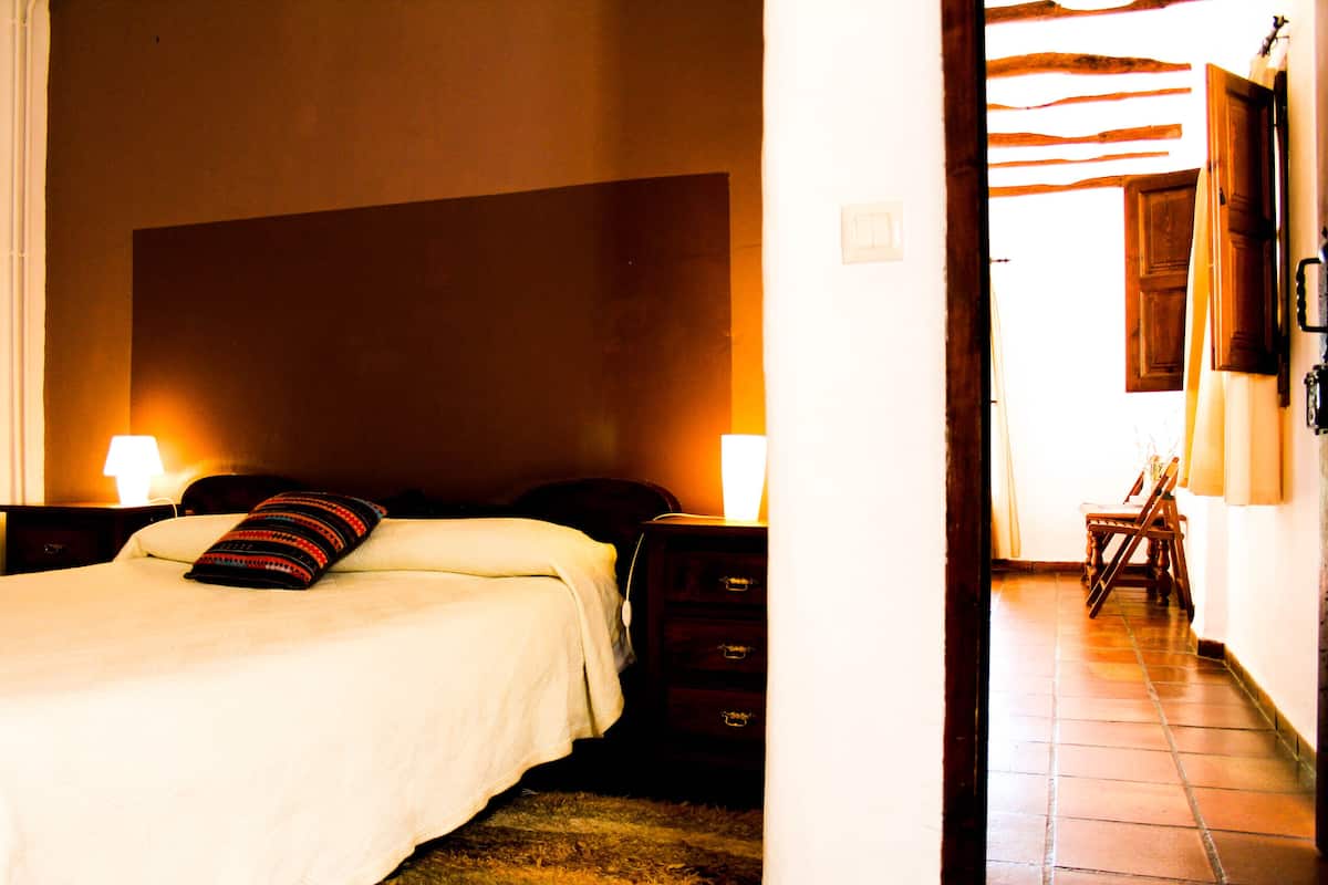 A bedroom with a bed, nightstands, and a wooden dresser.