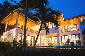 Uma casa moderna de dois andares com varanda, grandes janelas e área de piscina.