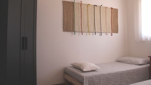 Een slaapkamer met een bed, een garderobe en een wandtapijt.