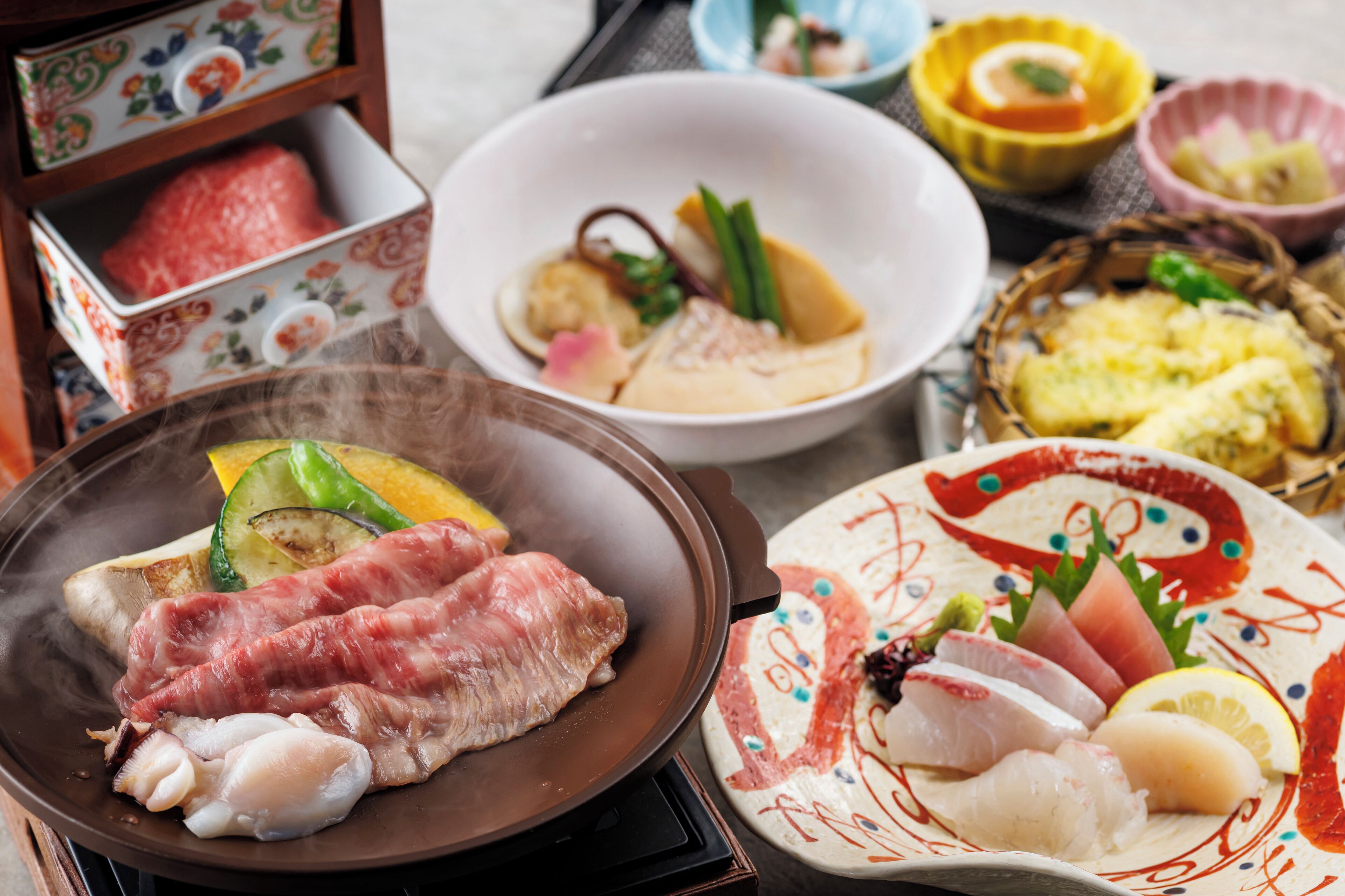 Una variedad de platos que incluyen sashimi, verduras a la parrilla y un tazón de arroz.