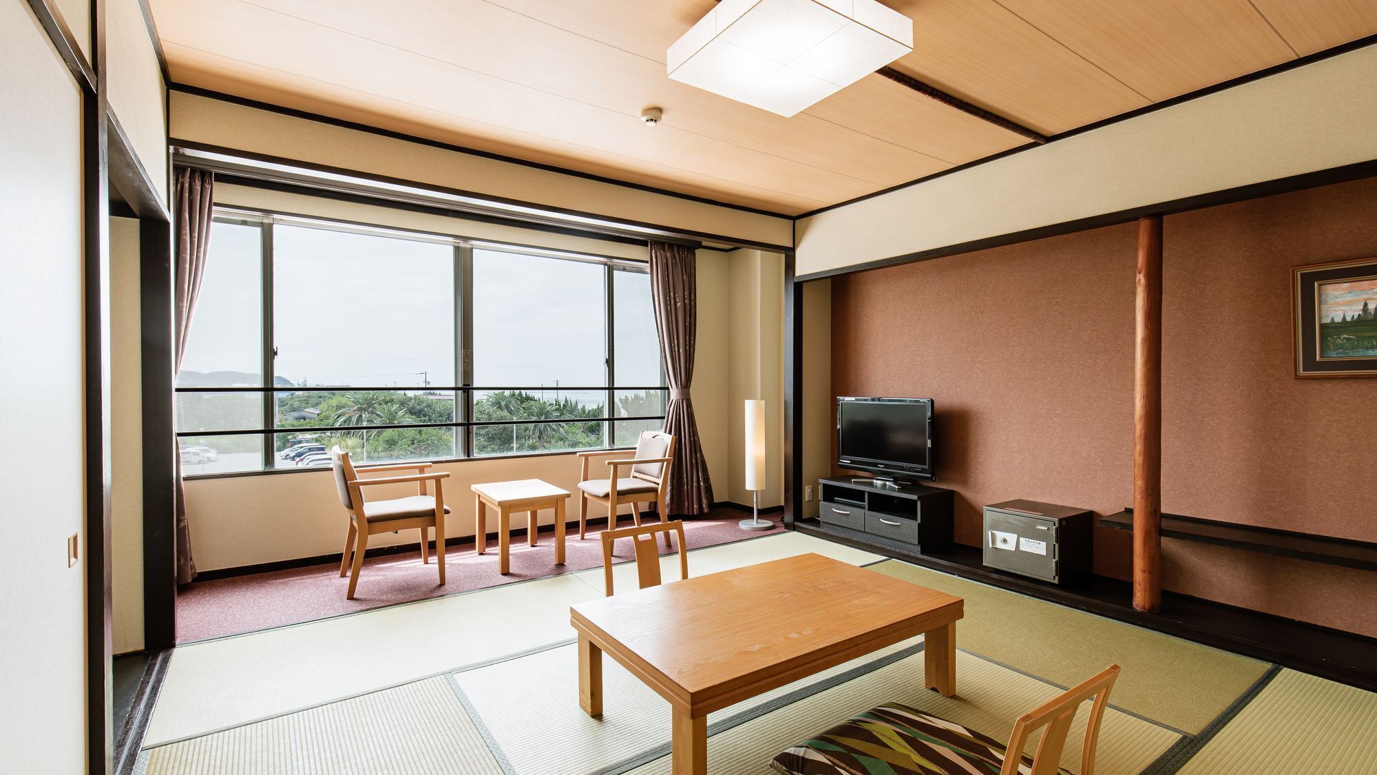 A hotel room with tatami flooring, a wooden table, four chairs, a television, and a cabinet.