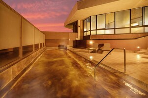 Una piscina interior climatizada con pared de vidrio, una banca y una silla.