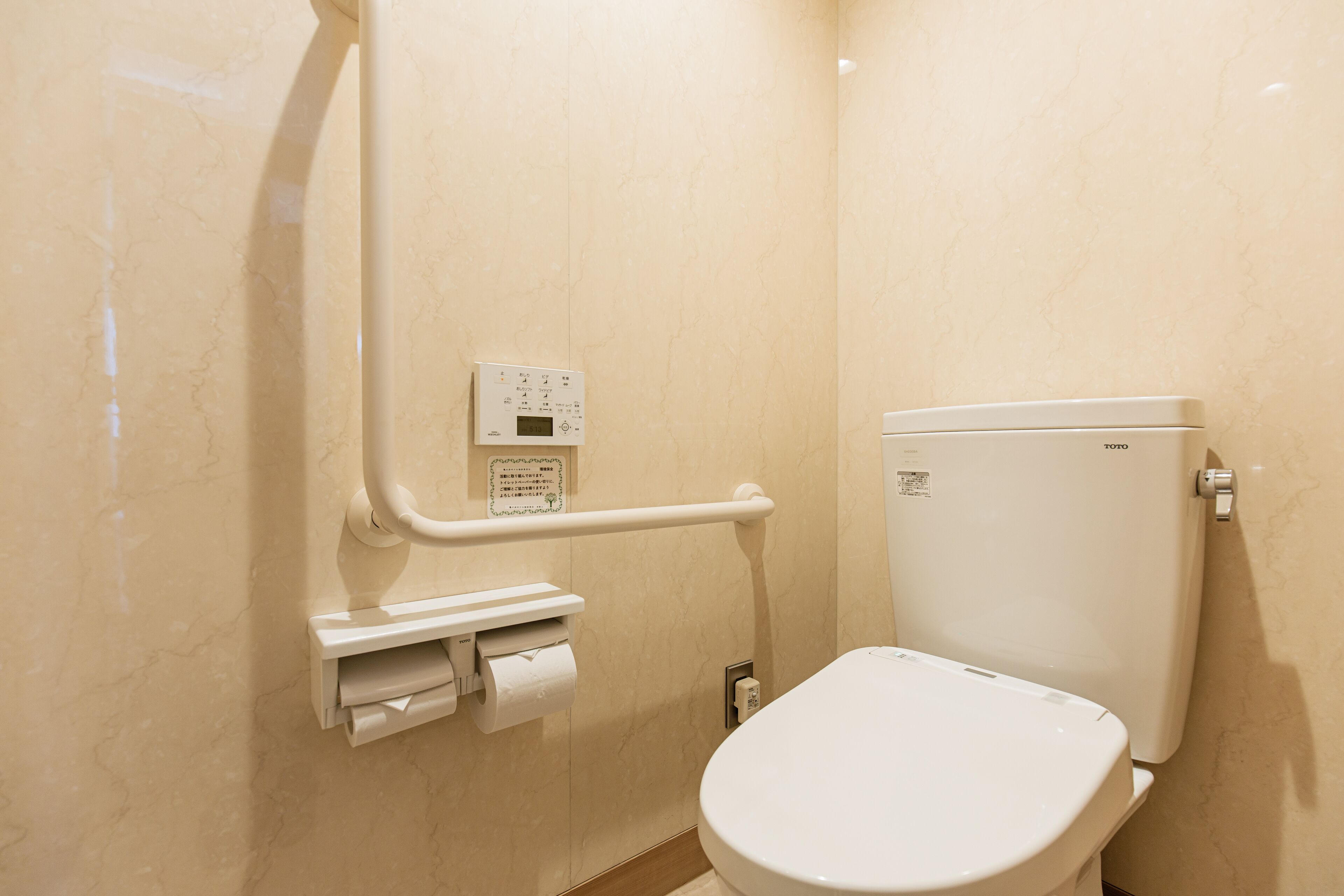 Un baño pequeño con inodoro, barandilla y panel de control.