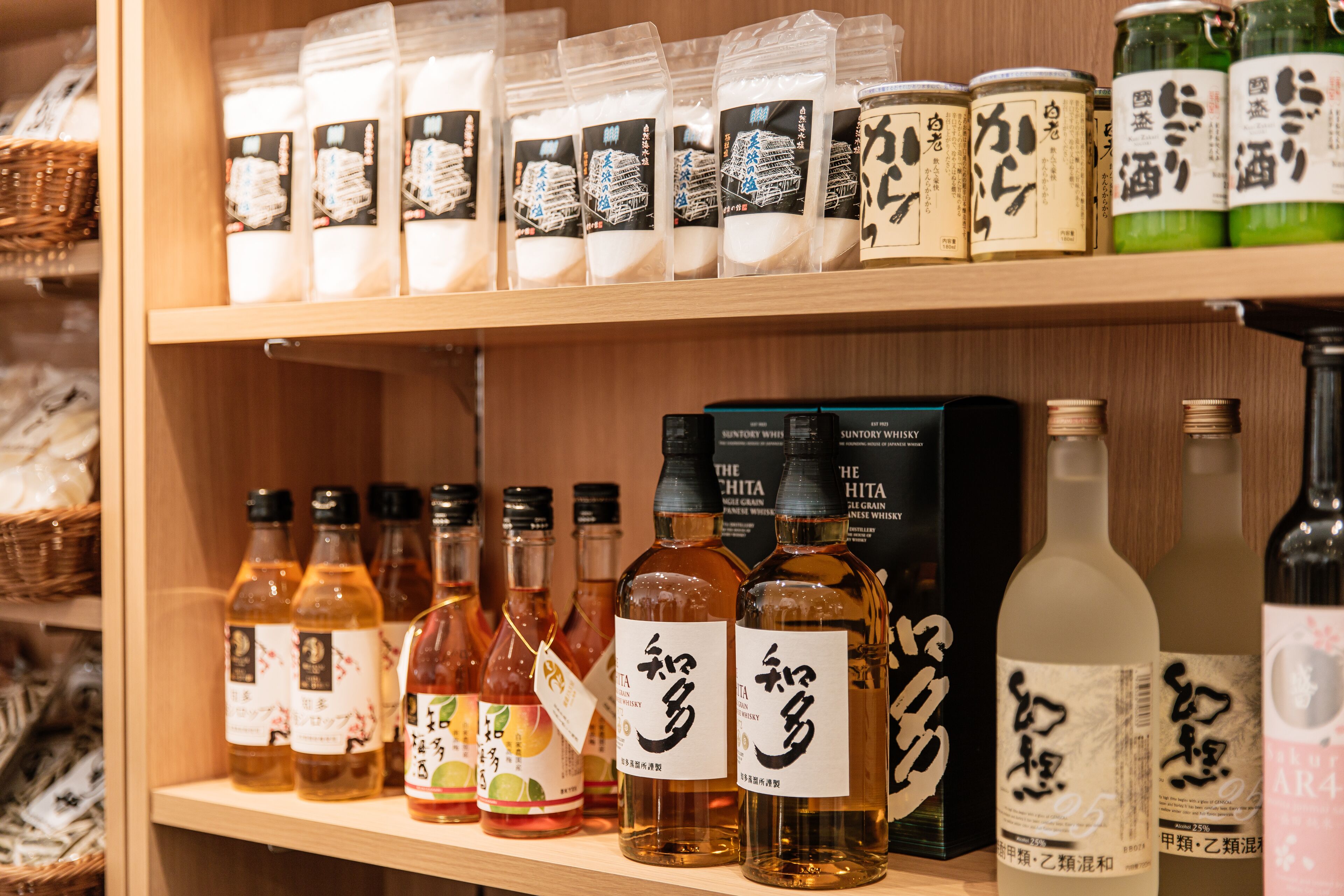 Una estantería con varias botellas y frascos, algunos con etiquetas y otros con caracteres japoneses.