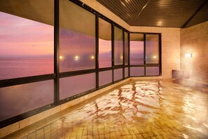 Un área de spa con vistas al mar al atardecer, suelo de cerámica y techo de madera.