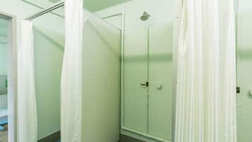 A bathroom with a shower area, a door, and a blue mat on the floor.