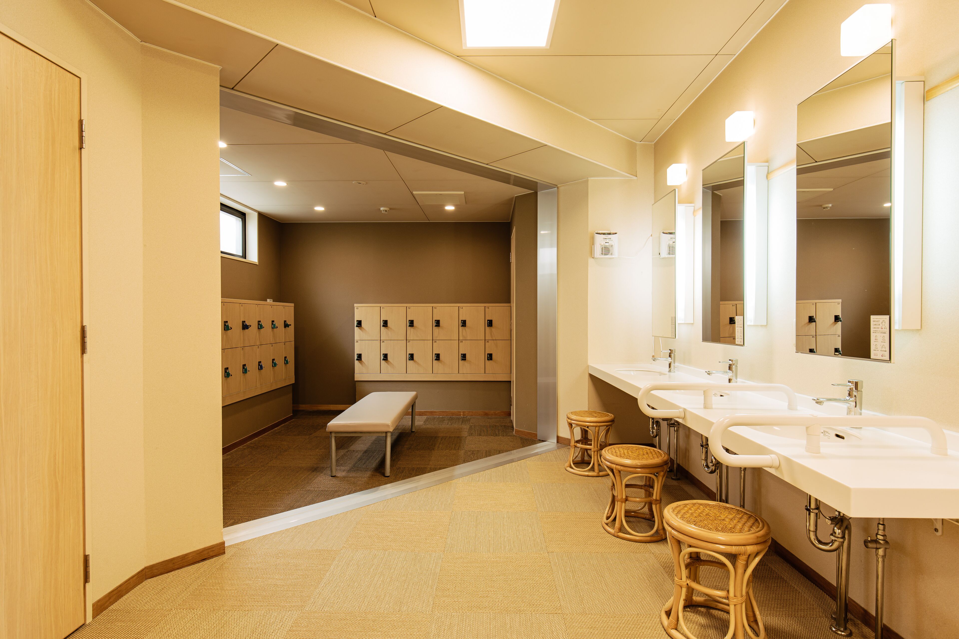 A hotel bathroom with multiple sinks, mirrors, and a bench.