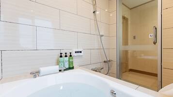 A modern bathroom with a large bathtub, a glass-enclosed shower, and a toilet.