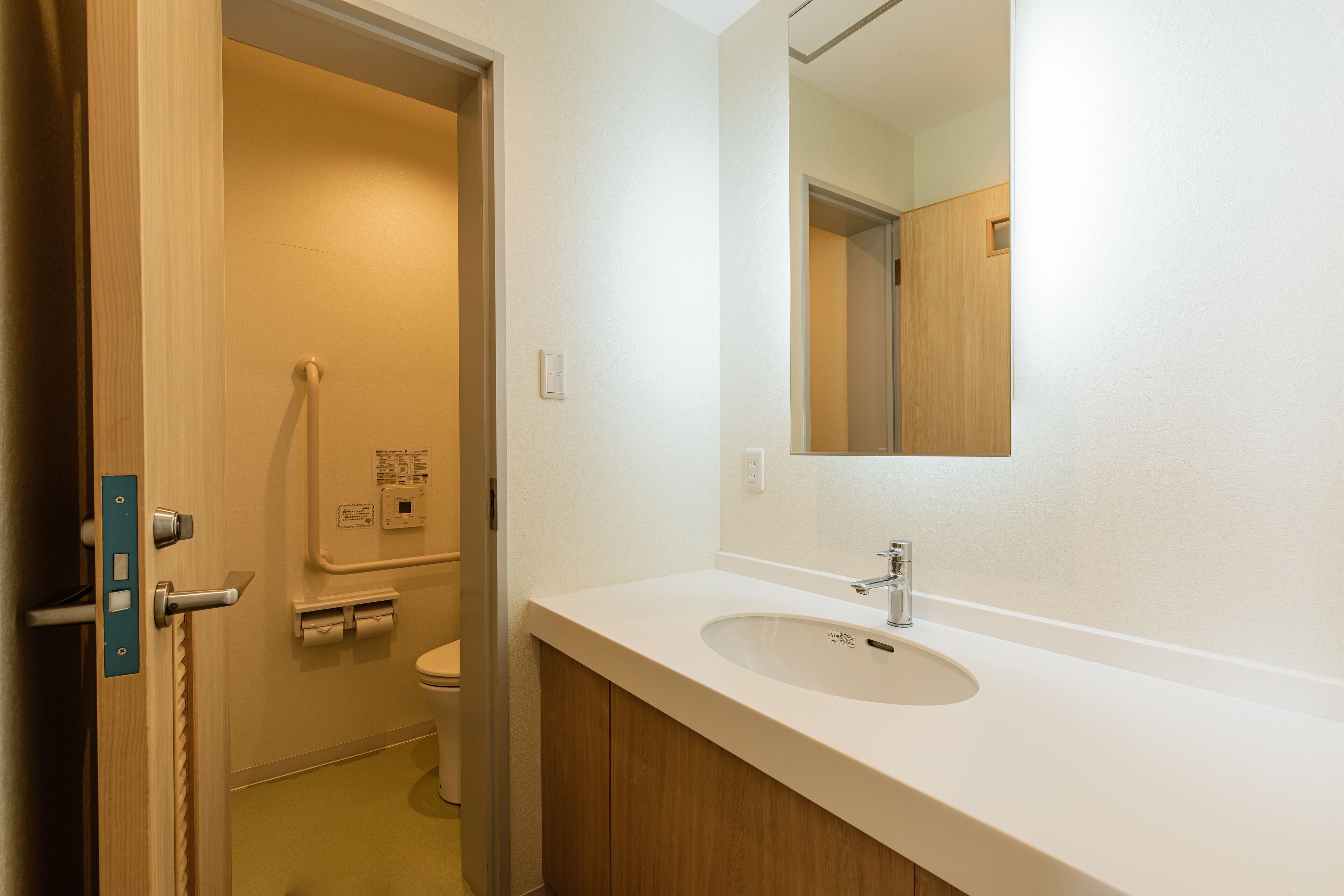 Een badkamer met een wit wastafel, een spiegel en een toilet.