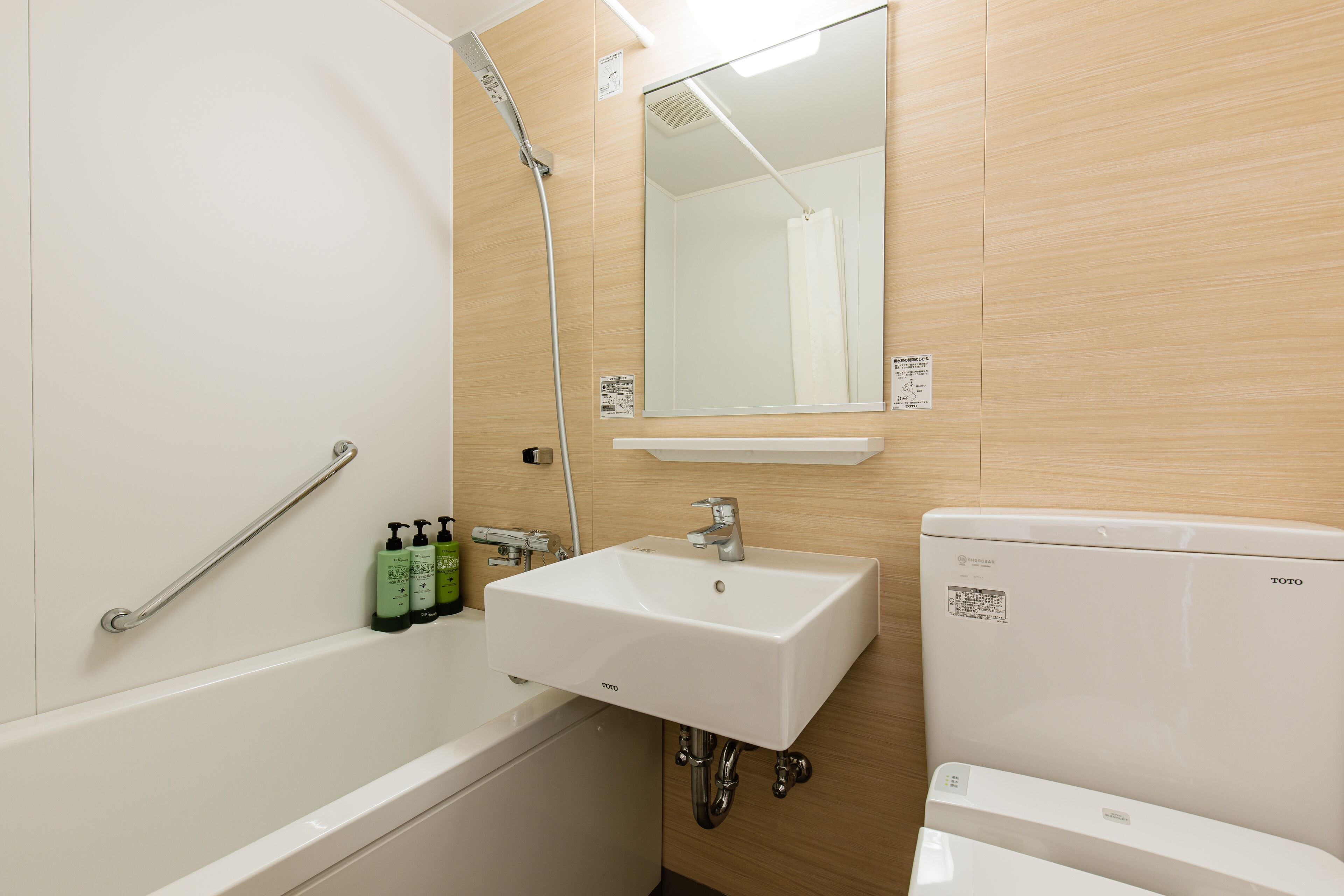 A bathroom with a white bathtub, a sink, and a toilet. There is a mirror above the sink and a showerhead above the bathtub.