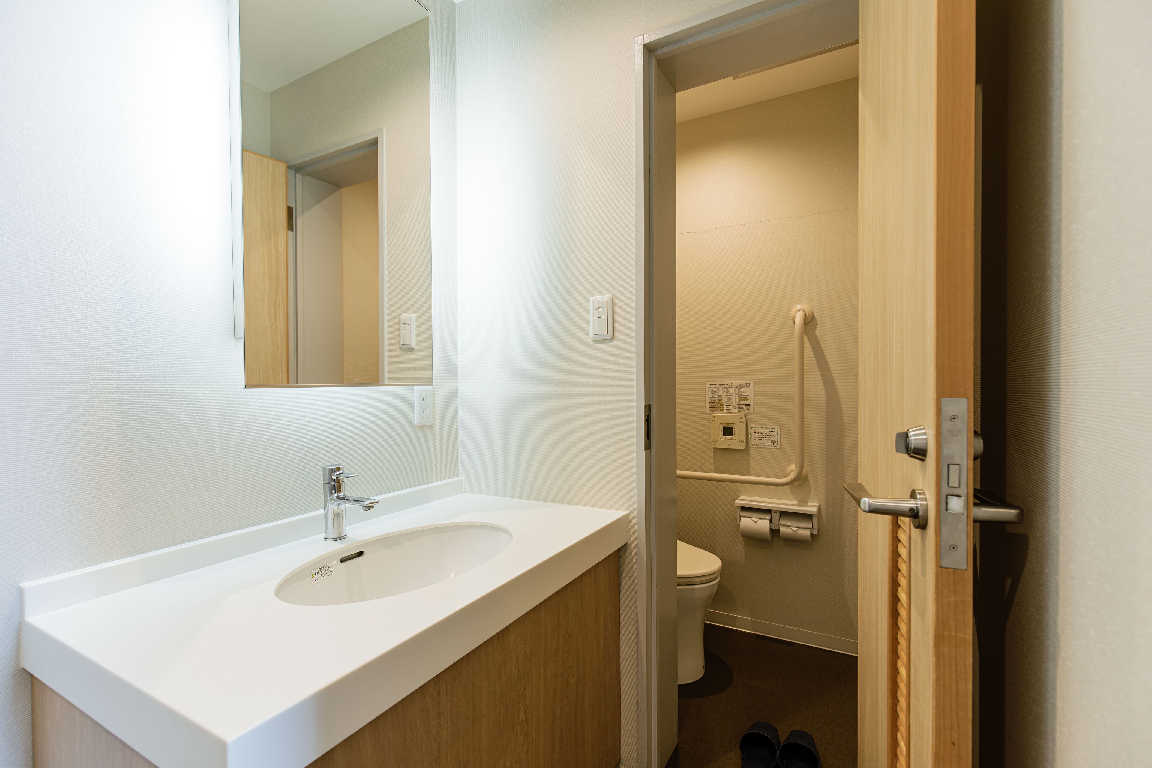 A bathroom with a white sink, mirror, and toilet.