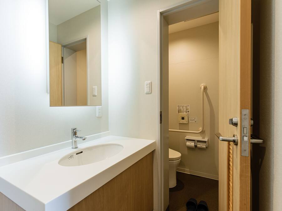 A bathroom with a white sink, mirror, and toilet.