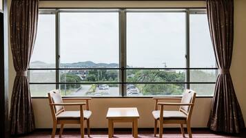 Ein Zimmer mit großem Fenster, zwei Stühlen und einem kleinen Tisch.