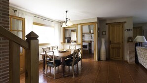 A dining area with a wooden table and chairs, a kitchen in the background, and a staircase leading to another level. - Finca La Cerquilla in Segovia (one hour from Madrid) (Ventosilla y Tejadilla)