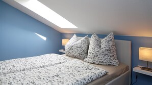 A bedroom with a skylight, a bed with floral bedding, and two bedside lamps. - comfortable apartment f. 3 pers., Central, modern furnishings, WLAN, incl. bed linen (Ostseebad Prerow)
