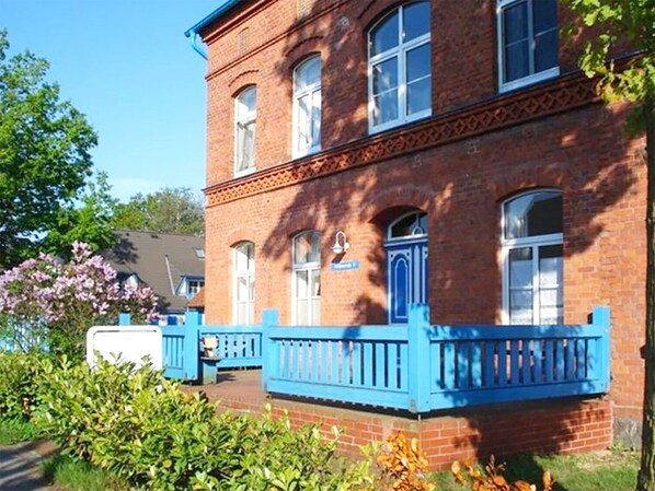 A two-story brick building with a blue balcony and a small porch area. - comfortable apartment f. 3 pers., Central, modern furnishings, WLAN, incl. bed linen (Ostseebad Prerow)