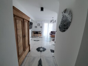 Um corredor com porta de madeira, área de jantar com mesa e cadeiras, e uma obra de arte com padrão de zebra na parede.