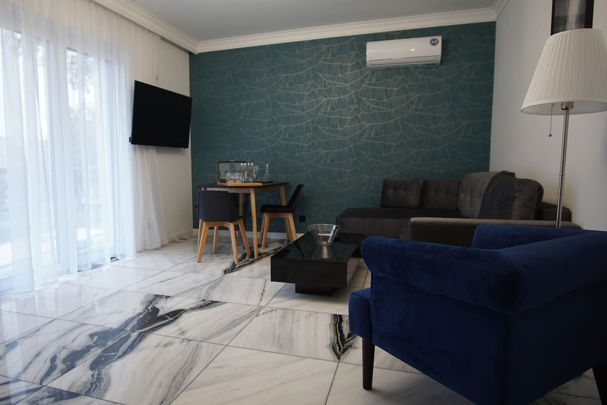 A modern living room with a blue sofa, a coffee table, and a TV mounted on the wall.