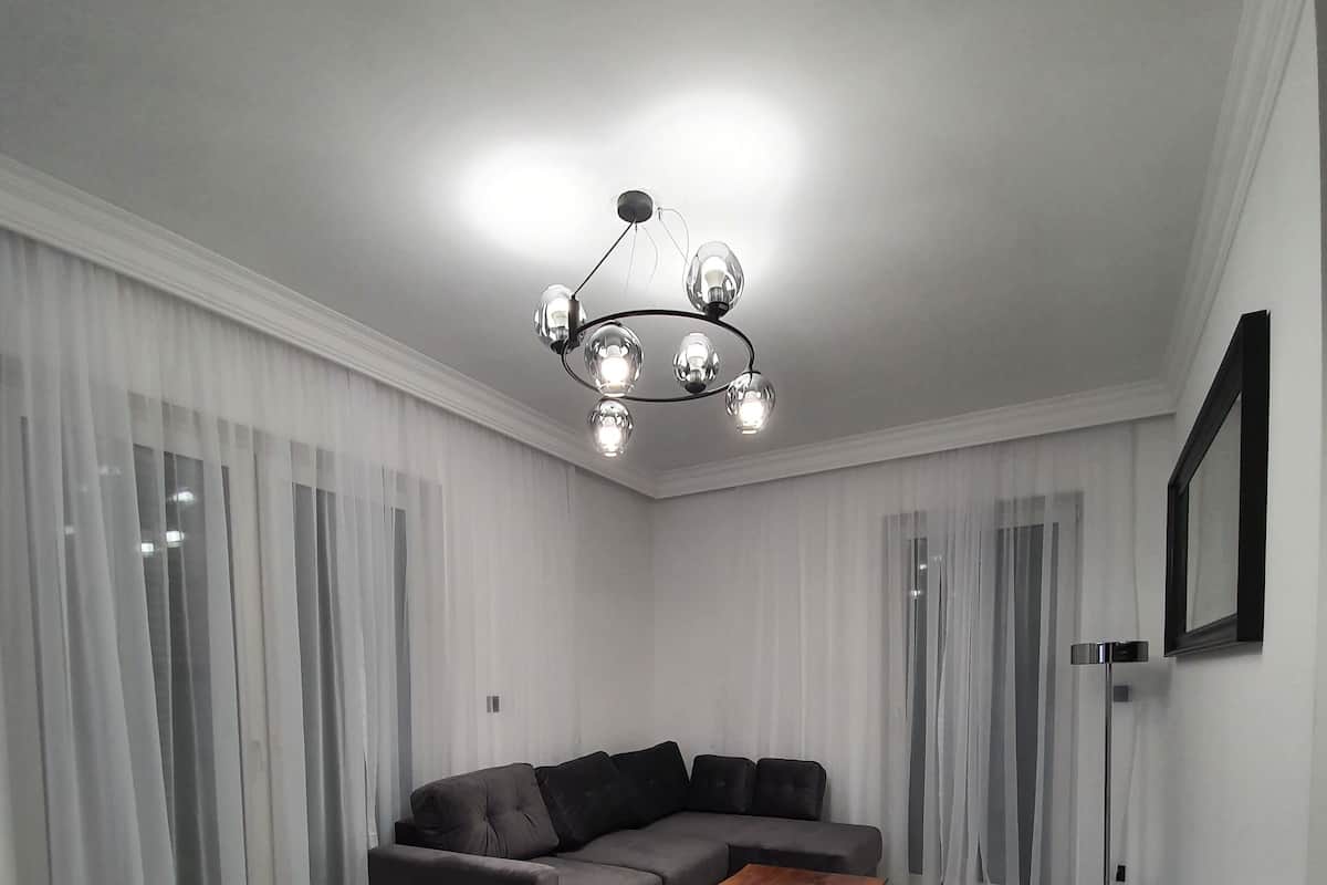 A modern living room with a sectional sofa, a wooden coffee table, and a chandelier.