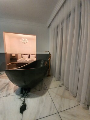 A modern bathroom with a freestanding bathtub, a wall-mounted sink, and a large mirror. - Korda Apartments (Swinoujscie)