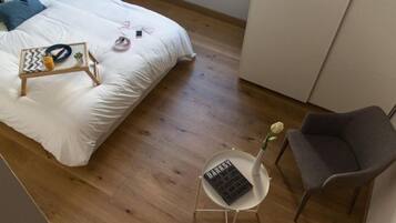 A bedroom with a bed, bedside table, chair, and a small table with a vase and a book.