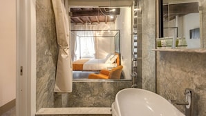 A bathroom with a marble wall, a bathtub, and a shower. - Residenza Argileto Arancione (Rome)