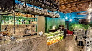 A bar area with shelves of bottles, a coffee machine, and a display of fruits. - Residenza Argileto Arancione (Rome)